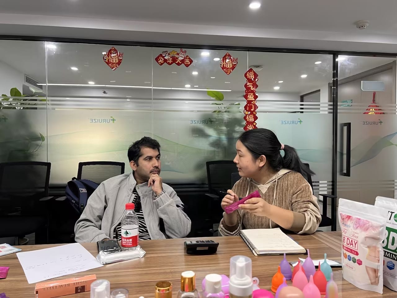 Product education session with our Pakistani visitors reviewing menstrual cup samples, costs, and margin structure